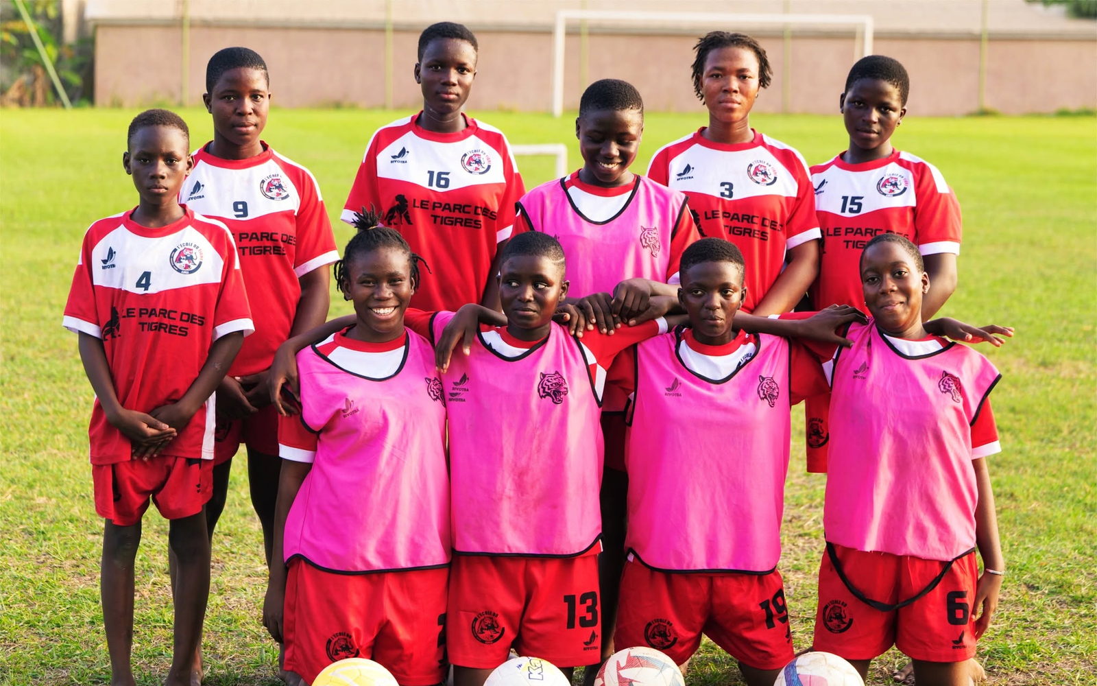Onze joueuses de l'École du Tigre posent en équipe sur la pelouse du Parc des Tigres, en maillot du club et chasubles d'entraînement.
