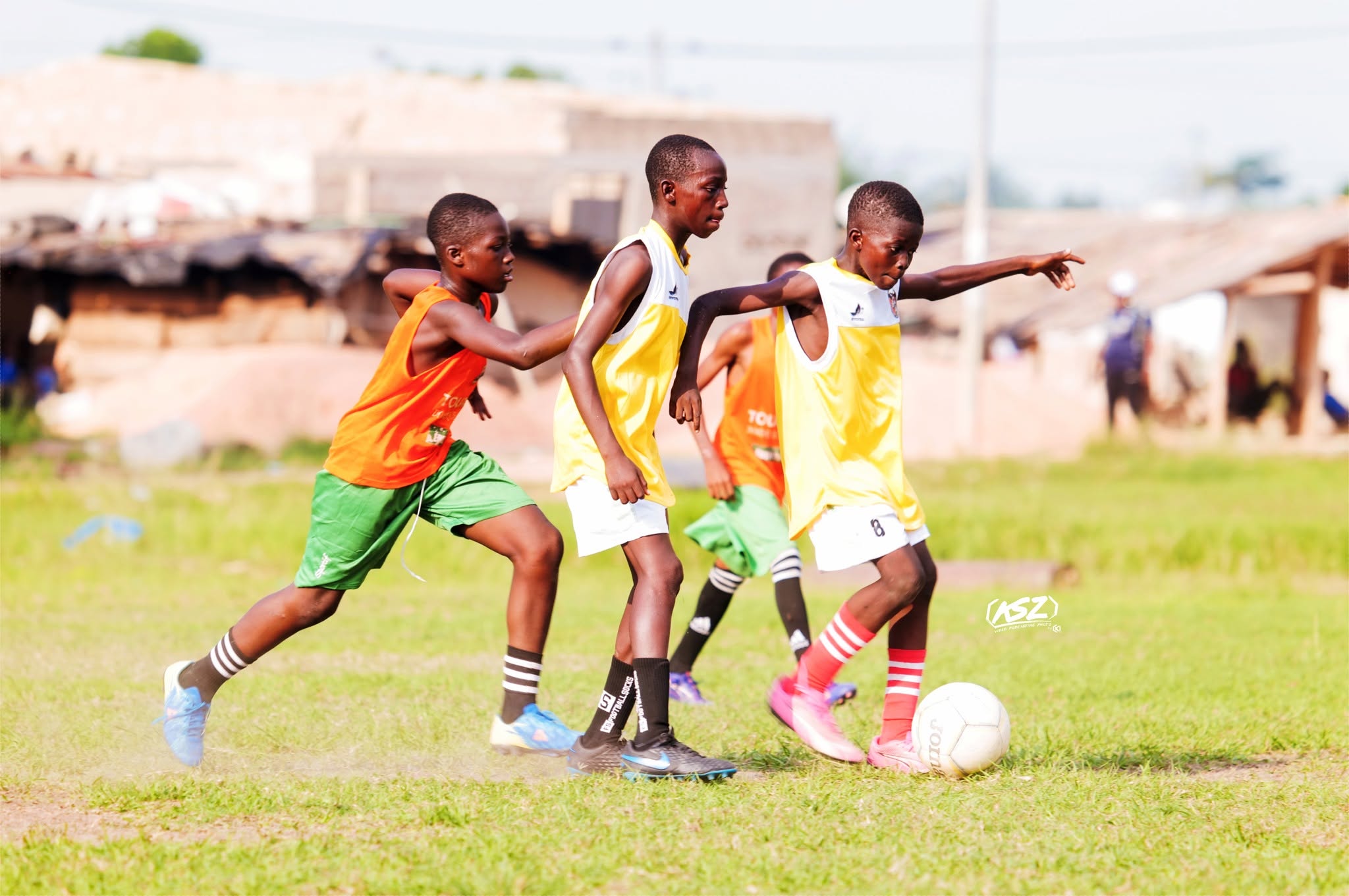 Trois jeunes joueurs de l'École du Tigre à la lutte pour le ballon, sur un terrain d'Adzopé.